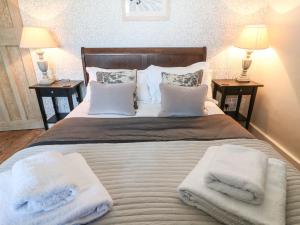 a bedroom with a bed with towels on it at Green Pump Cottage in Blockley