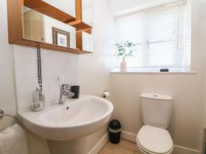 a bathroom with a sink and a toilet and a window at Green Pump Cottage in Blockley +20 photos