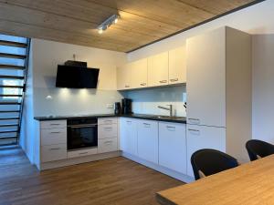 a kitchen with white cabinets and a table with chairs at Haus Wiesenquelle, Deluxe-Apartment 'Feld & Berg' in Feldberg
