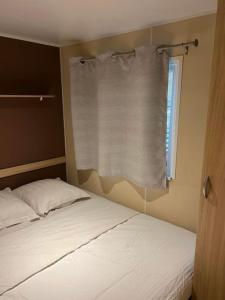 1 dormitorio con cama y ventana con cortina en Mobil-Home des Iscles, en La Roque-d'Anthéron