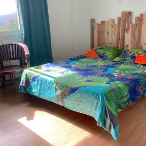 ein Bett mit farbenfroher Decke in einem Schlafzimmer in der Unterkunft Maison a Bourg- Murat proche de la cité du volcan in La Plaine des Cafres