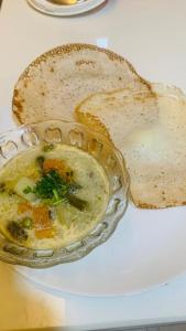 a bowl of soup on a table with a piece of bread at Mother's Inn Homestay in Cochin