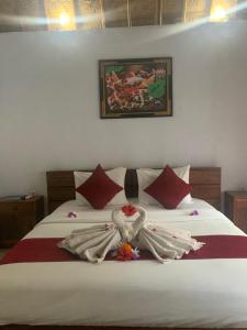 Jona Bungalow في نوسا بينيدا: غرفة نوم بسرير ذو شراشف بيضاء ومخدات حمراء