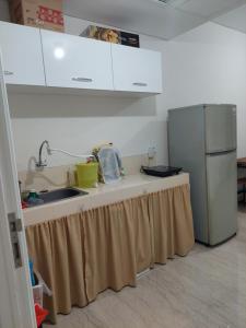 a kitchen with a counter with a sink and a refrigerator at Apartment Podomoro City Deli Medan in Medan