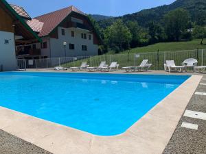 uma piscina azul com cadeiras e uma casa em Petit cocon entre lac, golf et montagne, proche d'Annecy em Giez