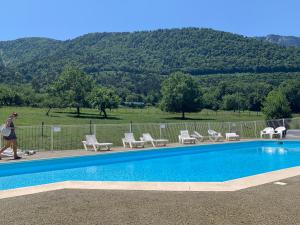 a woman walking by a swimming pool with chairs and a mountain at Petit cocon entre lac, golf et montagne, proche d'Annecy in Giez