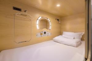 Bett in einem kleinen Zimmer mit Spiegel in der Unterkunft Luma Casa Capsule Hotel, Sunsuria Forum Setia Alam in Shah Alam