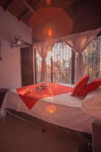 Schlafzimmer mit einem Bett mit roten Kissen und einem Fenster in der Unterkunft Hotel Palma De Sevilla in Medellín