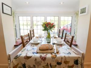 a dining room table with a table cloth with chickens on it at Cowfair Cottage in Chipping Campden