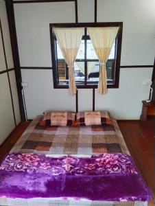 Cama grande en habitación con ventana en ชมไพรโฮมสเตย์ chomprai homestay, en Amphoe Chiang Dao