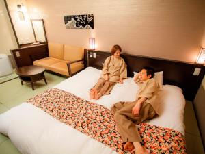 two people sitting on a bed in a hotel room at Takayama Ouan in Takayama