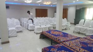 a man standing in a room with white chairs at The King Hotel in Multan