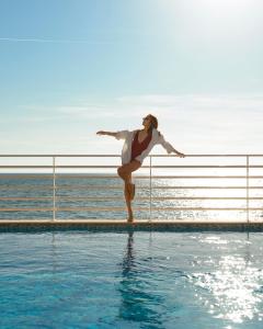 a woman standing on a fence next to a swimming pool at Hotel Miramare Stabia in Castellammare di Stabia