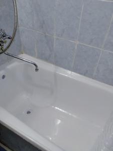 bañera blanca con grifo en el baño en Seaside apartment, en Aktau