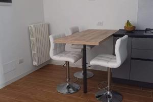 a kitchen with a wooden table and white chairs at Spilamberto 6b - 12mins from San Donato M3 station in San Donato Milanese +3 photos