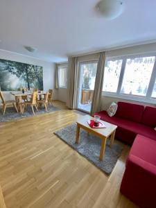 - un salon avec un canapé rouge et une table dans l'établissement Appartements "ALPS" by Kamper, à Obertauern