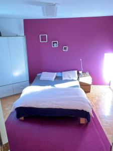 Fioletowa sypialnia z dużym łóżkiem i fioletową ścianą w obiekcie Petite maison choux w mieście Bouillon