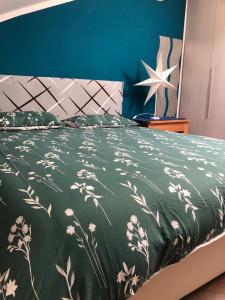 a bed with a green blanket with flowers on it at Tra Stadio e Storia - Fronte Allianz Stadium Juventus in Venaria Reale