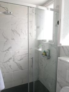 ein Bad mit einer Dusche und weißen Marmorfliesen in der Unterkunft Studio confortable à Guéthary 30 m² avec balcon relaxant in Guéthary