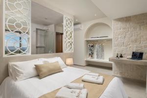 a bedroom with a white bed and a stone wall at Sohora twin Villas in Xirostérnion