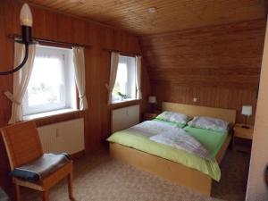 a bedroom with a bed and two windows and a chair at Pension Gaststätte Tannenhof in Saupsdorf