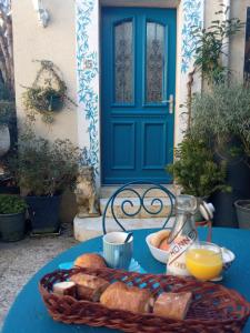 einen Tisch mit einem Korb Brot und einer blauen Tür in der Unterkunft MYSaintAubin in Saint-Aubin-sur-Mer