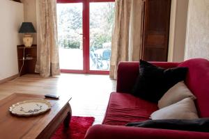 a living room with a red couch and a table at Gîte de la Grange in Saint-Pardoux