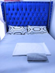 - un lit bleu avec une tête de lit bleue et une serviette dans l'établissement Bamburi Luxury Homes 2, à Bamburi