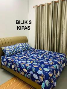 a bed in a bedroom with a blue blanket and curtains at Spar Homestay in Kota Bharu