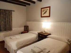 a room with two beds and a table with a lamp at Viviendas Rurales El Covaju in Cabezón de Liébana