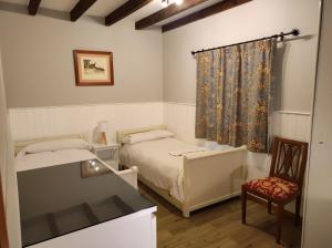 a bedroom with two beds and a chair and a window at Viviendas Rurales El Covaju in Cabezón de Liébana