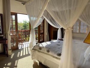 a bedroom with a canopy bed and a balcony at Jembisa Bush Home in Melkrivier