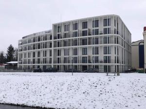 un gran edificio blanco con nieve delante en Apartament Mazagran en Zamość