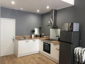 a kitchen with white cabinets and a black refrigerator at Appartement Duplex 8 personnes proche télécabines in Ax-les-Thermes +3 photos