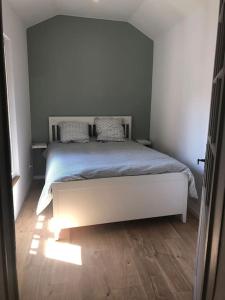 a bedroom with a white bed with a blue blanket at Appartement Duplex 8 personnes proche télécabines in Ax-les-Thermes