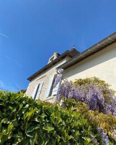 Un bâtiment avec un bouquet de fleurs violettes sur lui dans l'établissement Le pigeonnier de Saint-Loup Bed and Breakfast, à Saint-Loup-de-Varenne