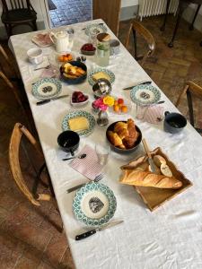 una mesa con un mantel blanco con comida. en Le pigeonnier de Saint-Loup Bed and Breakfast, en Saint-Loup-de-Varenne
