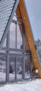een groot gebouw met grote ramen in de sneeuw bij Cabana Corbilor The Raven's Hut in Vatra Dornei