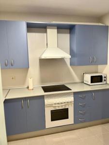 una cocina con armarios azules y un horno de fogón blanco en Marina Serena Golf 1ª linea Playa, en Roquetas de Mar