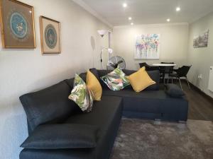 a living room with a blue couch with pillows at Rest-a-While Guest House - Pretoria in Pretoria