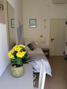 a room with a bed and a vase of yellow flowers at Alevon Hotel in Rimini