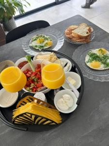 una bandeja de alimentos para el desayuno en una mesa con vasos de zumo de naranja en יחידה מושלמת ברמת ישי לזוג או יחיד, en Ramat Yishay