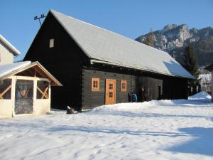 a black barn with snow in front of it at Chalupa pod lipami in Terchová