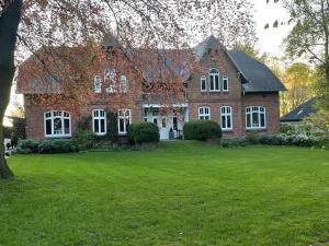 una gran casa de ladrillo con un gran patio en Ferienwohnung Landhaus, en Maasbüll