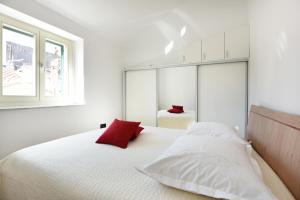 a bedroom with a white bed with a red pillow at Apartment Kokolo in Šibenik