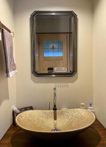 een wastafel in een badkamer met een grote spiegel bij 浪漫宿花町 in Mitarai