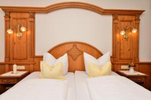 a bedroom with two beds with white sheets and yellow pillows at Hotel-Pension Seebad "Seegenuss-Natur-Spa" in Sulzberg