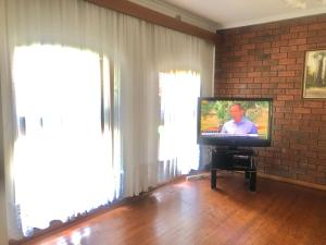 a television in a living room with two windows at Golden House in Springvale