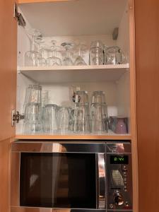 a kitchen cabinet filled with glasses and a microwave at Sonnenchalet mit Sauna in Kötschach