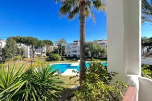 basen z palmą obok budynku w obiekcie Costalita - 2 bedroom apartment 350m from the beach w mieście Estepona +8 zdjęć